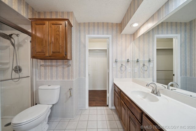 bathroom with toilet, a textured ceiling, tile patterned flooring, vanity, and a shower with door