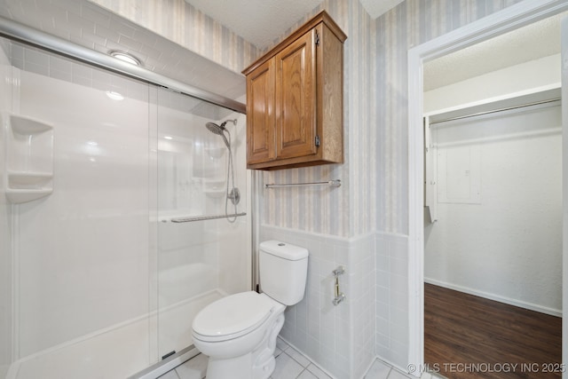 bathroom featuring tile patterned floors, toilet, and walk in shower