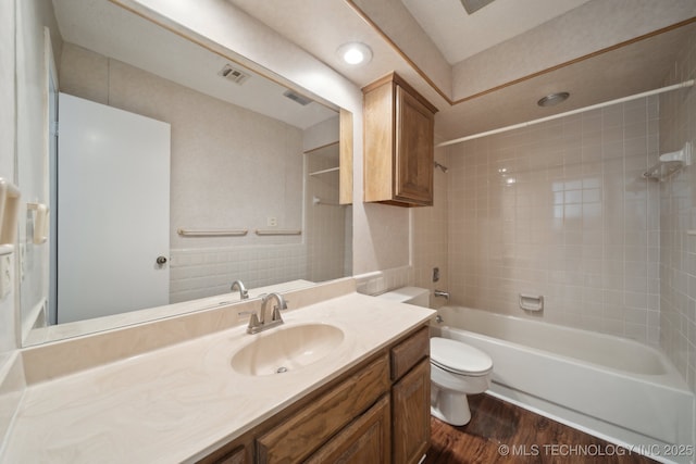 full bathroom featuring hardwood / wood-style floors, toilet, vanity, and tiled shower / bath combo