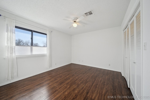 unfurnished bedroom with ceiling fan, a textured ceiling, and dark hardwood / wood-style flooring