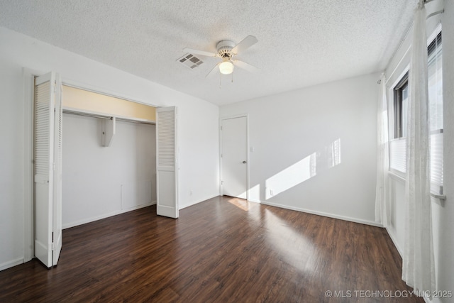 unfurnished bedroom with a closet, ceiling fan, dark hardwood / wood-style floors, and a textured ceiling