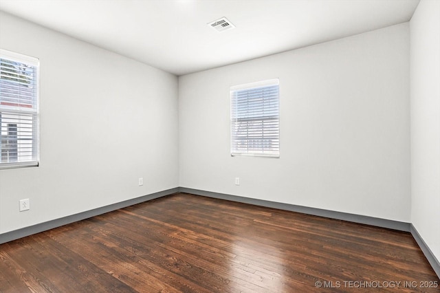 spare room with dark hardwood / wood-style floors and a healthy amount of sunlight