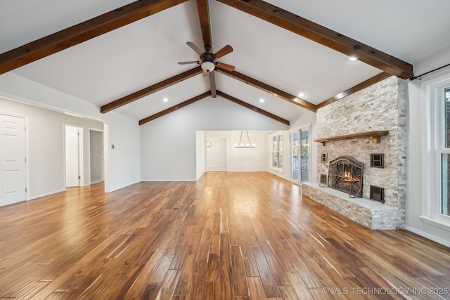 unfurnished living room featuring hardwood / wood-style floors, vaulted ceiling with beams, ceiling fan with notable chandelier, and a fireplace