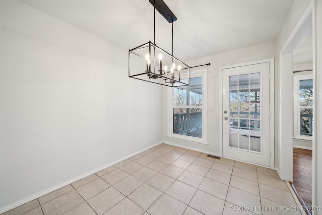 unfurnished dining area featuring light tile patterned flooring and a chandelier