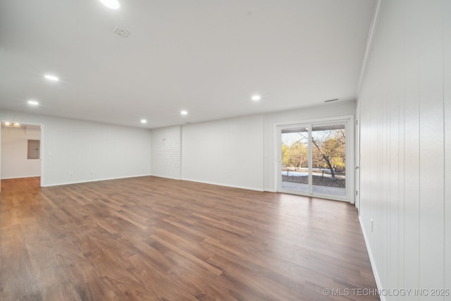 spare room featuring hardwood / wood-style floors, wooden walls, and electric panel