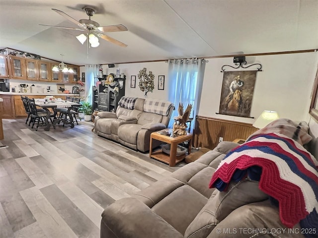 living room featuring ceiling fan, light hardwood / wood-style flooring, and wooden walls