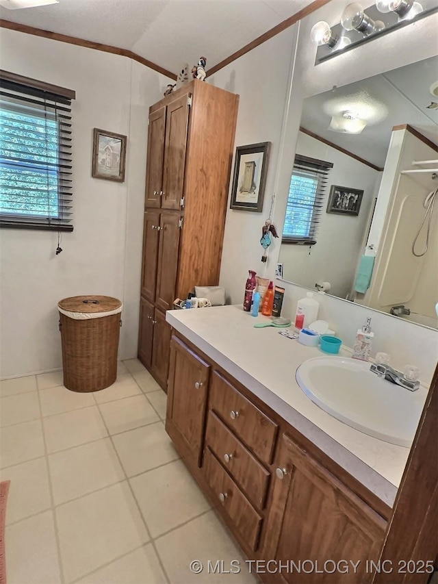 bathroom featuring vanity, tile patterned floors, crown molding, and lofted ceiling