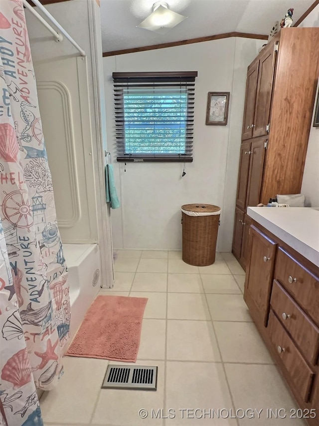 bathroom with shower / bath combo with shower curtain, tile patterned floors, ornamental molding, vanity, and vaulted ceiling