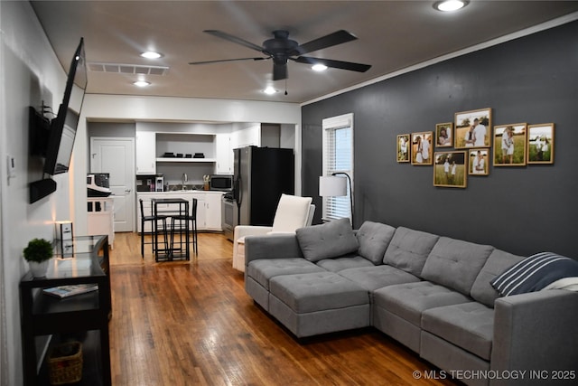 living room with crown molding, sink, ceiling fan, and dark hardwood / wood-style flooring