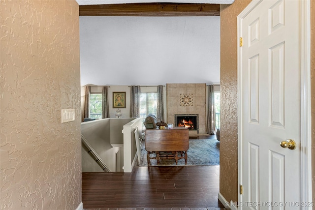 living room featuring beam ceiling, hardwood / wood-style flooring, and a tile fireplace