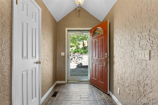 doorway featuring a textured ceiling and vaulted ceiling