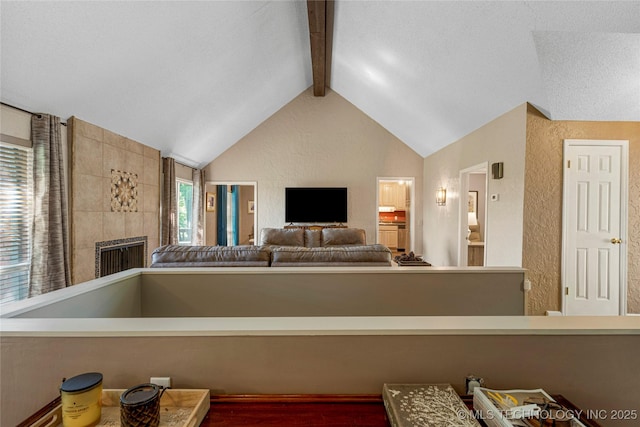 living room featuring a tile fireplace and vaulted ceiling with beams