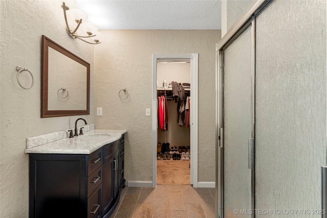 bathroom with a textured ceiling, an enclosed shower, and vanity