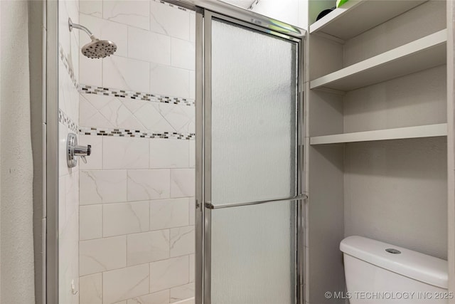 bathroom featuring toilet and a shower with shower door