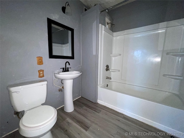 bathroom featuring wood-type flooring, bathtub / shower combination, and toilet