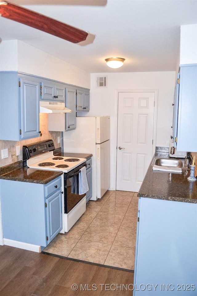 kitchen featuring electric stove, visible vents, a sink, blue cabinets, and under cabinet range hood