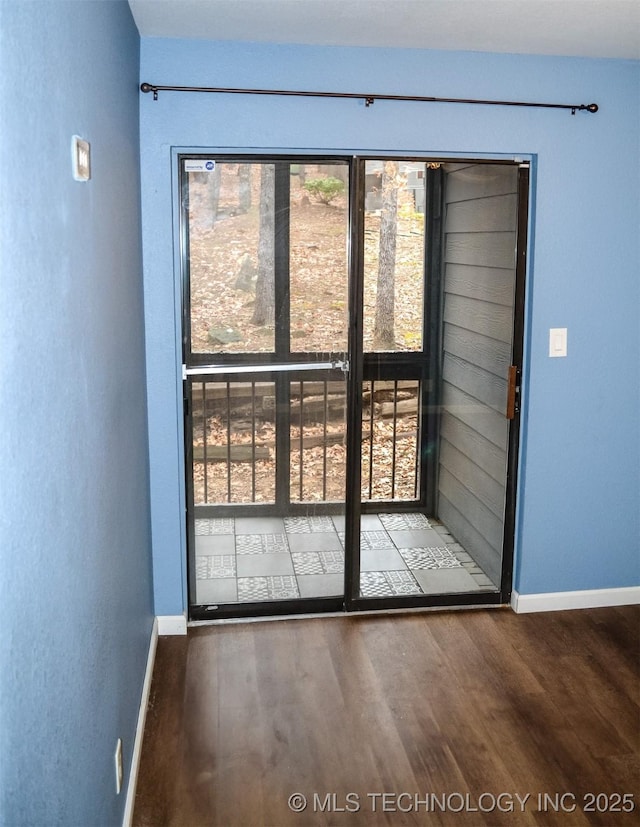 doorway to outside featuring baseboards and wood finished floors