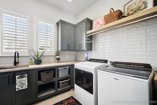 laundry room with light tile patterned floors, sink, separate washer and dryer, and cabinets