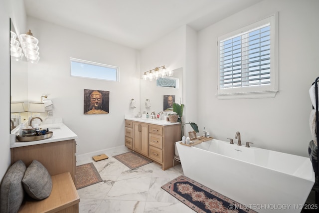 full bath featuring a freestanding tub, two vanities, a sink, and marble finish floor
