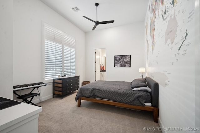 bedroom featuring a ceiling fan, light colored carpet, visible vents, baseboards, and ensuite bath