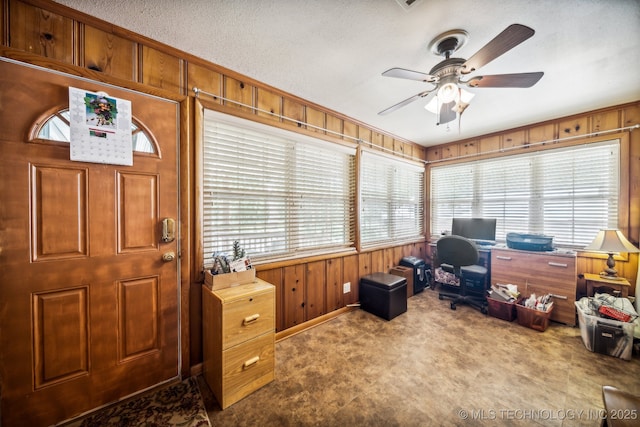 office space featuring ceiling fan, a healthy amount of sunlight, carpet, and wood walls