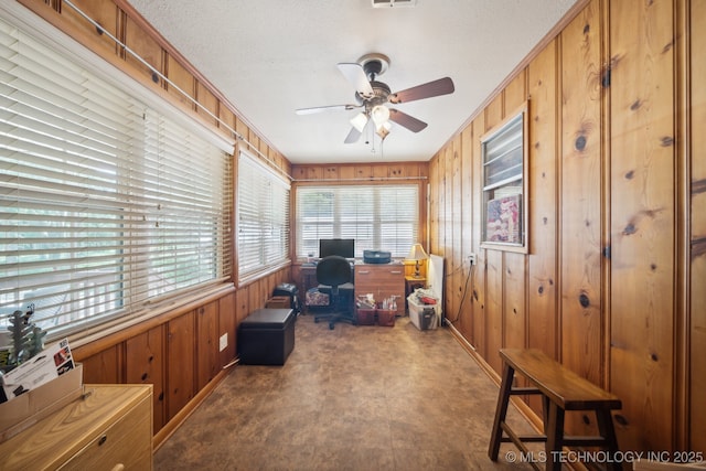 office with a textured ceiling, ceiling fan, and wood walls