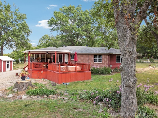 back of property featuring a wooden deck, a lawn, and an outbuilding