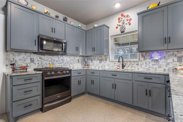 kitchen featuring sink, gray cabinetry, tasteful backsplash, appliances with stainless steel finishes, and light stone countertops