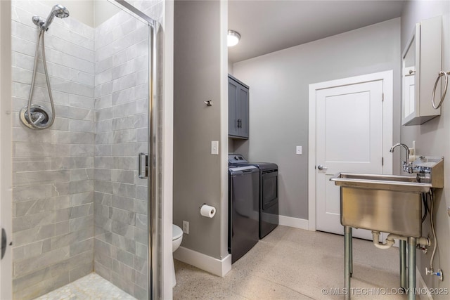 bathroom featuring sink, a shower with door, independent washer and dryer, and toilet