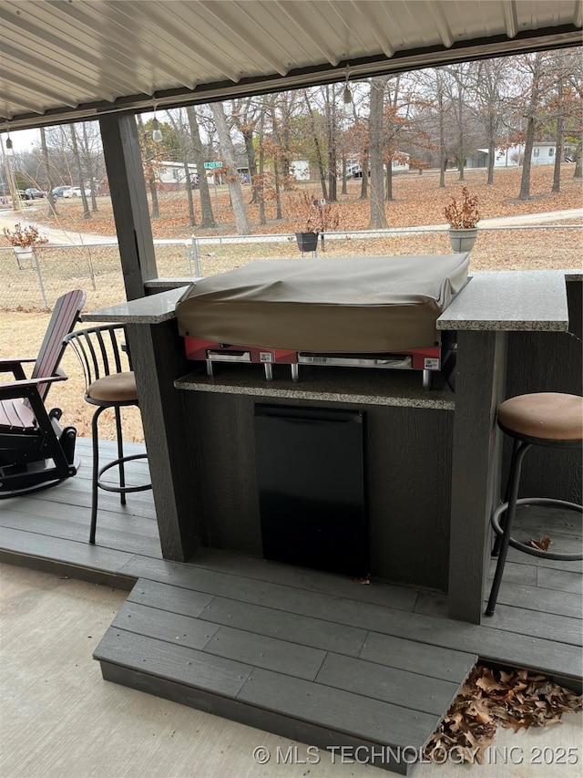 wooden deck with a hot tub, a playground, and an outdoor bar