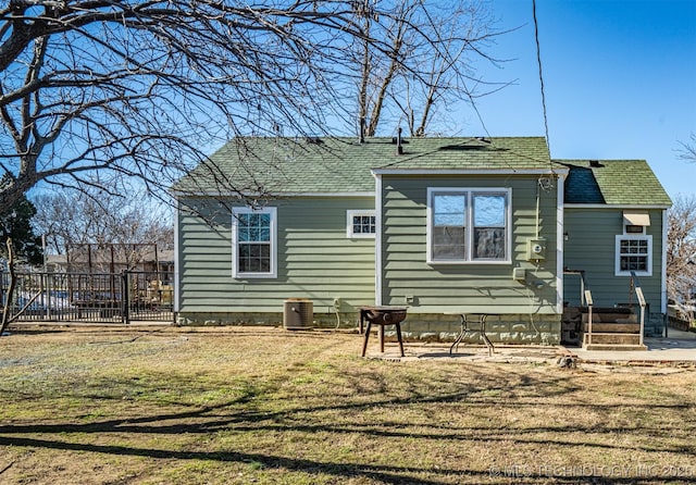 rear view of property with central air condition unit and a yard