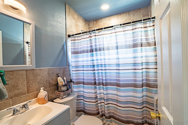 bathroom with curtained shower, tile walls, toilet, and vanity