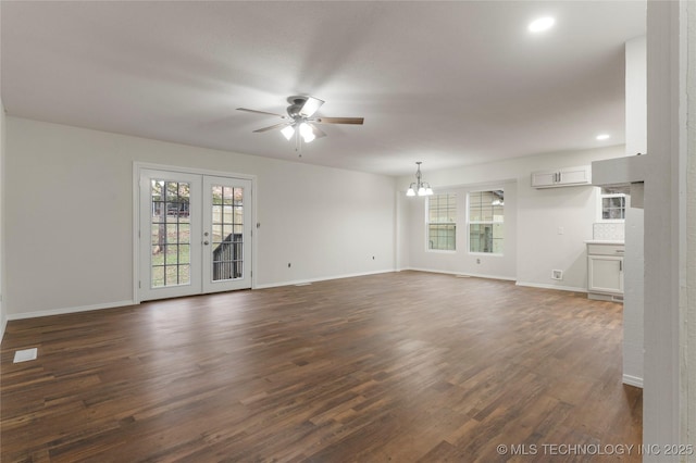 unfurnished living room featuring dark hardwood / wood-style flooring, ceiling fan with notable chandelier, and french doors