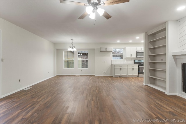 unfurnished living room with ceiling fan with notable chandelier and dark hardwood / wood-style floors