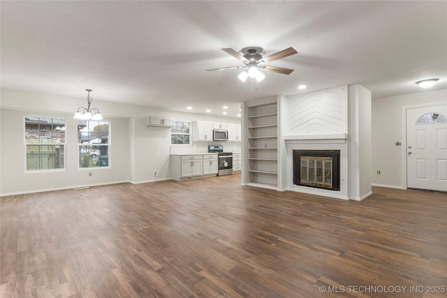 unfurnished living room featuring ceiling fan with notable chandelier, dark wood-type flooring, and a fireplace