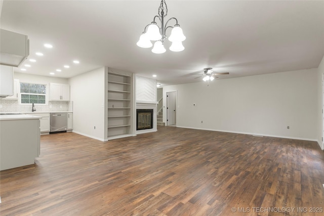 unfurnished living room with ceiling fan, built in shelves, dark hardwood / wood-style floors, and a fireplace