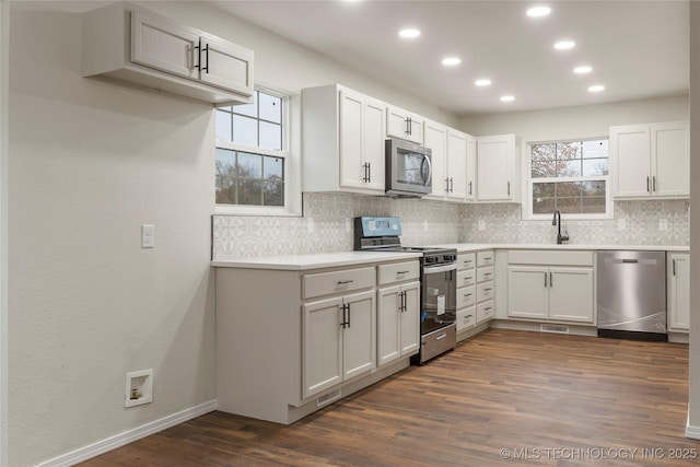 kitchen with white cabinets, appliances with stainless steel finishes, dark hardwood / wood-style flooring, and sink