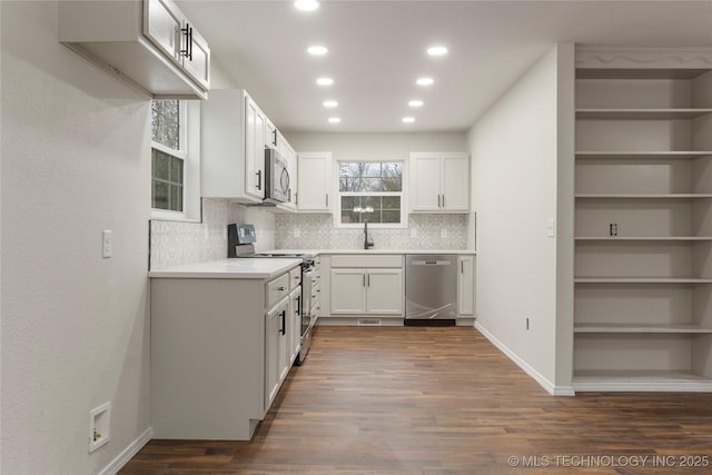 kitchen with appliances with stainless steel finishes, white cabinetry, decorative backsplash, sink, and dark hardwood / wood-style floors