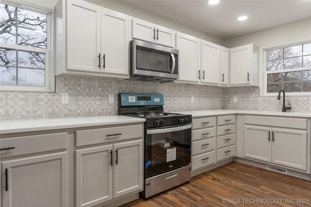 kitchen with dark hardwood / wood-style flooring, sink, white cabinets, a healthy amount of sunlight, and stainless steel appliances