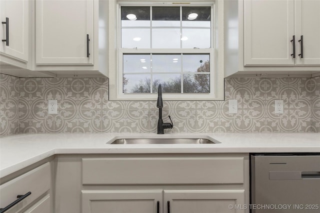 kitchen with sink, backsplash, white cabinetry, and stainless steel dishwasher