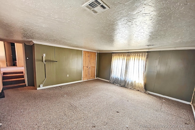 unfurnished bedroom featuring a textured ceiling, carpet floors, and ornamental molding