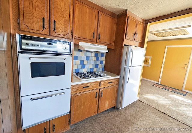 kitchen with a textured ceiling, white fridge, tasteful backsplash, gas cooktop, and dark carpet