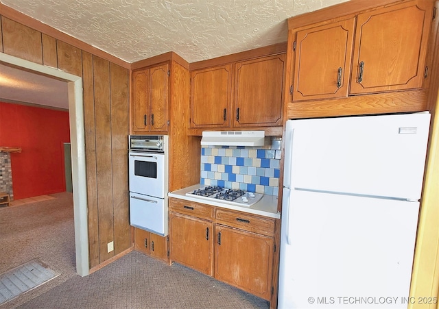 kitchen featuring white appliances, a textured ceiling, carpet floors, wood walls, and decorative backsplash