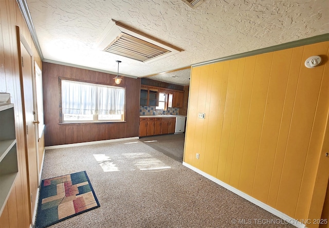 unfurnished living room with carpet floors, a textured ceiling, ornamental molding, and wooden walls