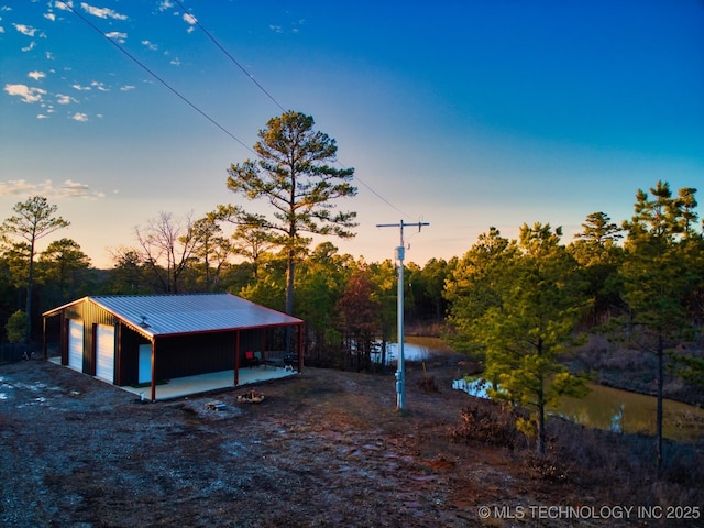 exterior space featuring a garage, a water view, and an outdoor structure