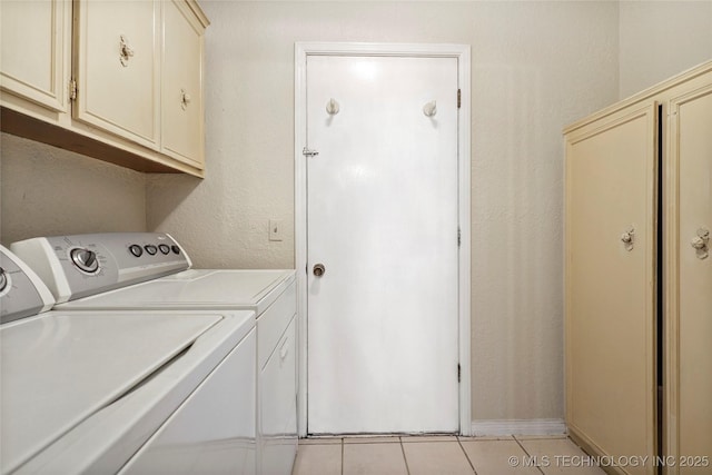 clothes washing area with cabinets, independent washer and dryer, and light tile patterned floors