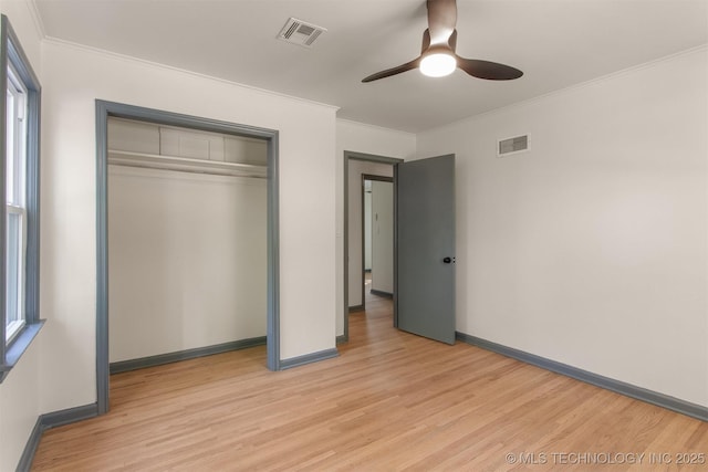 unfurnished bedroom with ceiling fan, a closet, ornamental molding, and light wood-type flooring