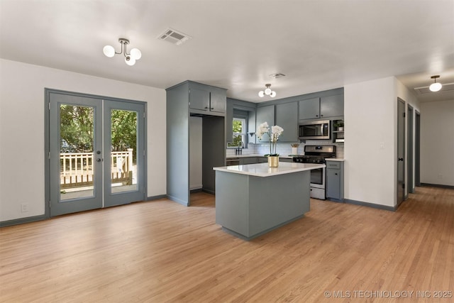 kitchen featuring appliances with stainless steel finishes, tasteful backsplash, sink, french doors, and light hardwood / wood-style flooring