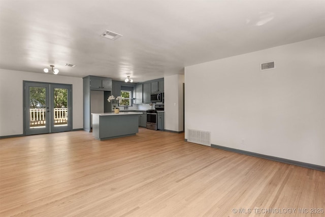 unfurnished living room with light hardwood / wood-style floors and french doors