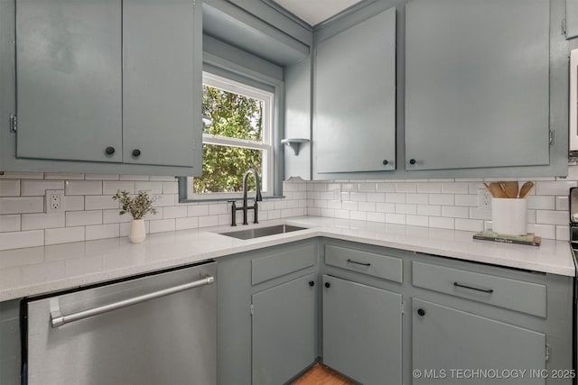 kitchen featuring sink, backsplash, stainless steel dishwasher, and gray cabinets